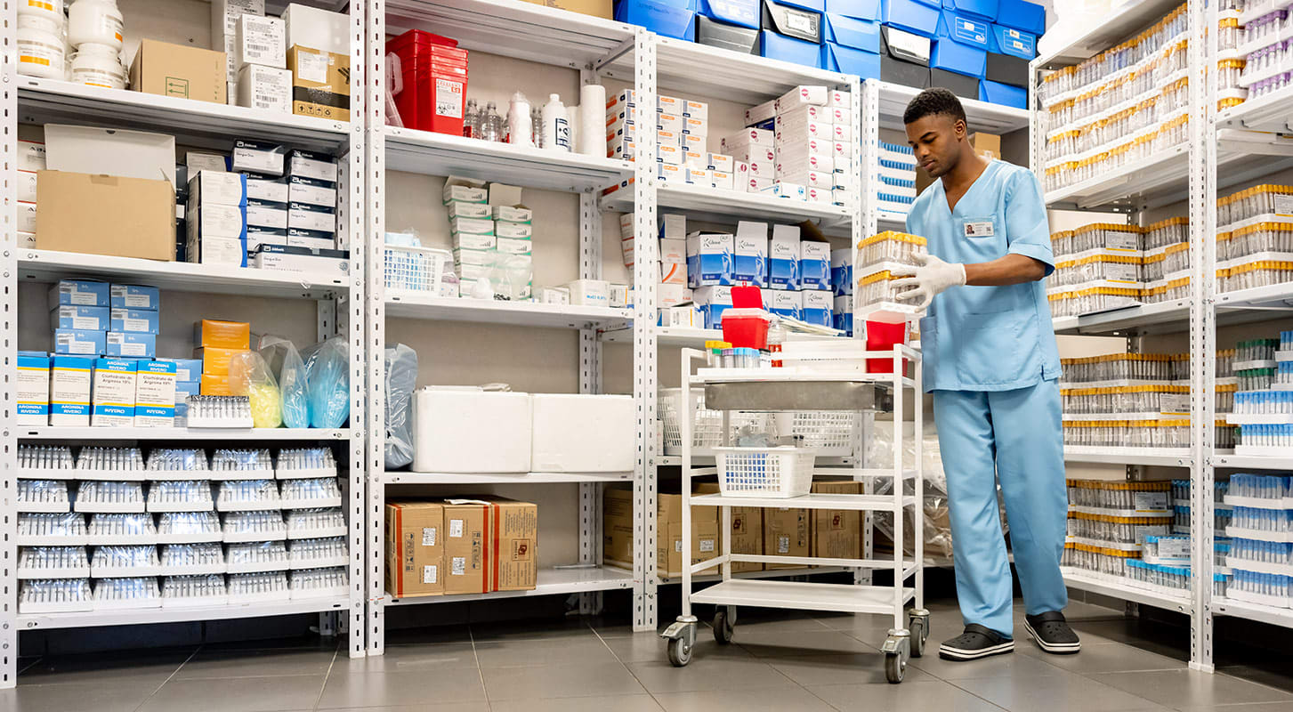 Medical staff member in a pharmacy stock room, picking up essential medical supplies.